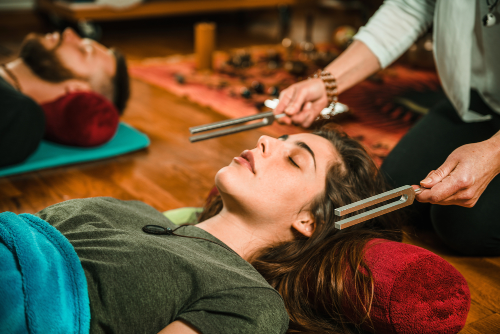 A woman laying with her eyes closed while receiving sound therapy highlighting the role of music in healing