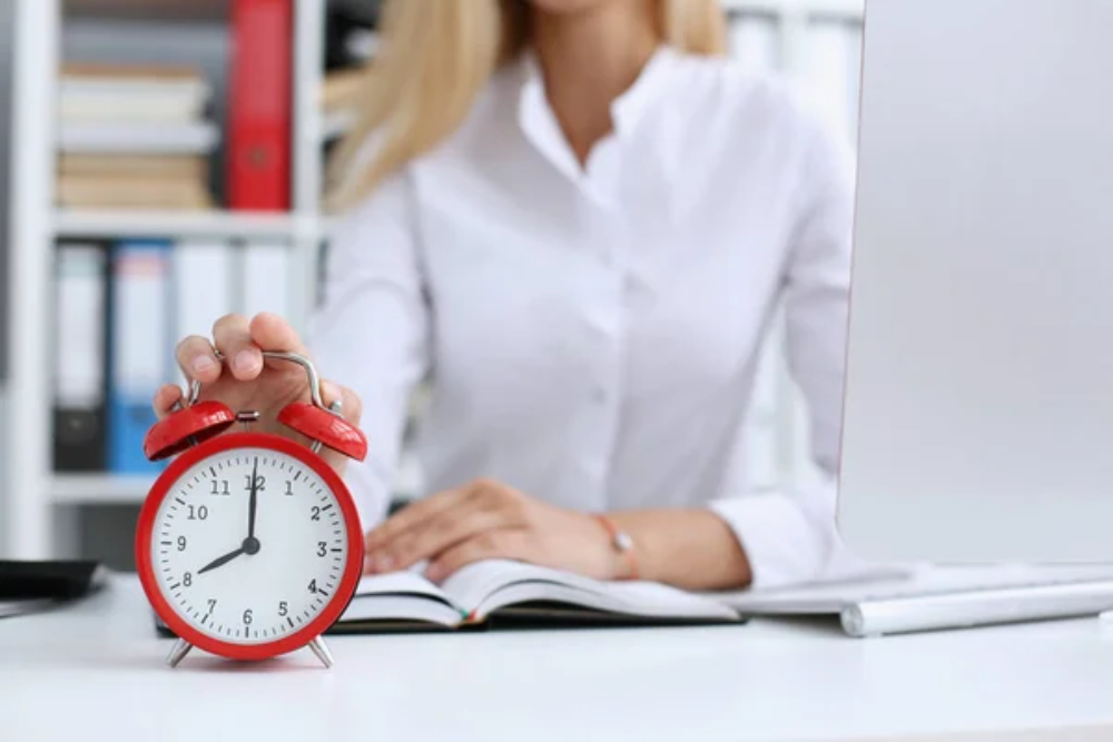 A woman resting her hand on a red analog clock
