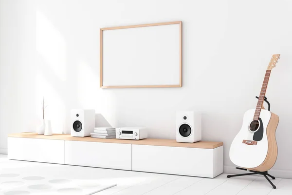 White smart speakers with a stereo sitting on a table next to a guitar